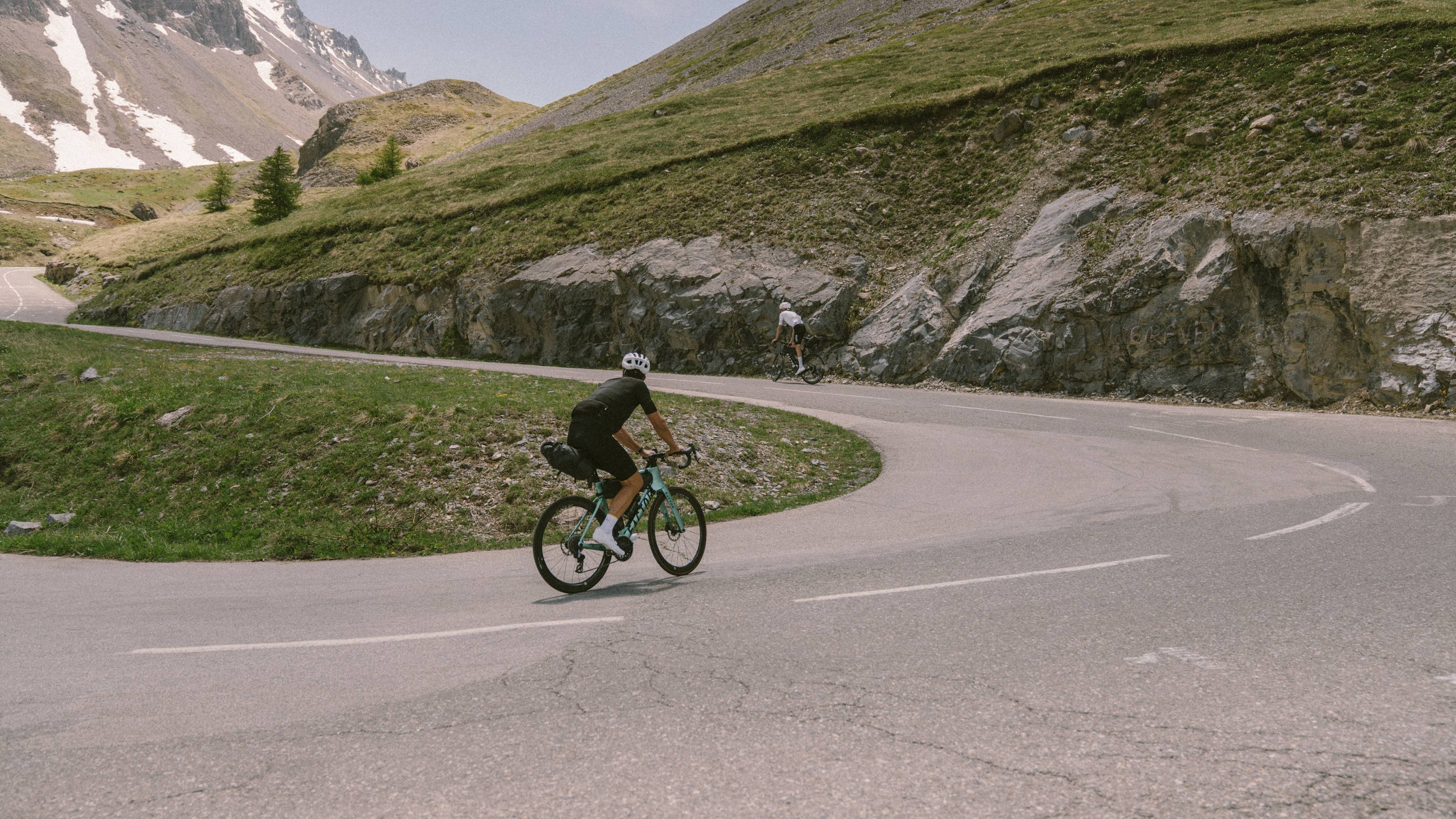 Image of two cyclists riding up a hill with a valley behind them.